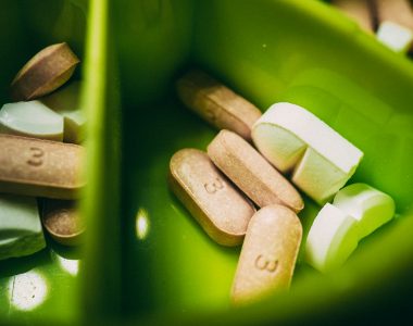 pílula de medicação branca em recipiente de plástico verde